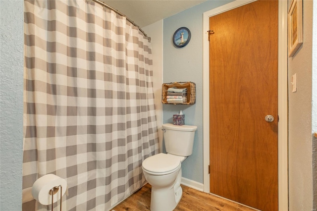 full bathroom featuring toilet, a shower with shower curtain, and wood finished floors