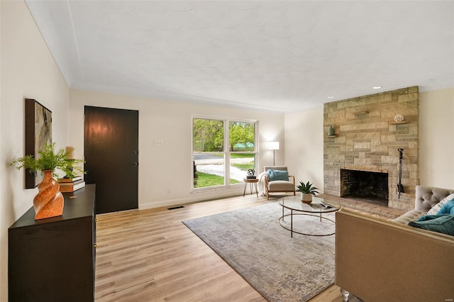 living room with visible vents, baseboards, light wood finished floors, and a fireplace