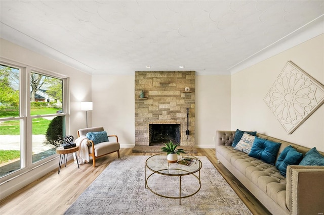 living room featuring light wood-type flooring, baseboards, and a stone fireplace