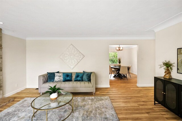 living room featuring crown molding, baseboards, an inviting chandelier, and wood finished floors