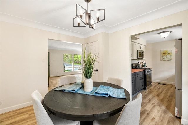 dining space with an inviting chandelier, visible vents, light wood-type flooring, and baseboards