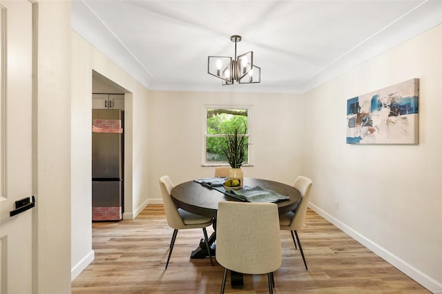 dining area with a chandelier, light wood finished floors, and baseboards