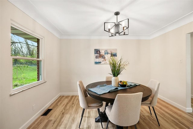 dining area featuring light wood finished floors, baseboards, visible vents, and a notable chandelier