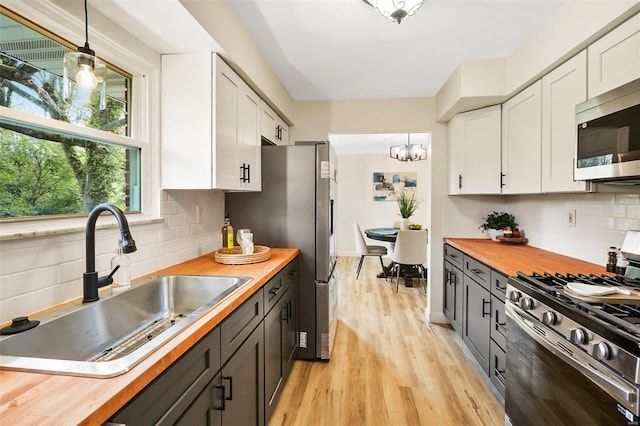 kitchen featuring white cabinetry, a sink, stainless steel appliances, wood counters, and light wood finished floors