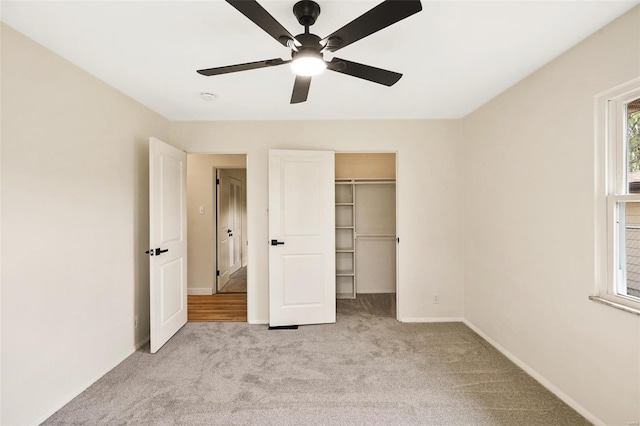 unfurnished bedroom with a closet, a ceiling fan, carpet flooring, a walk in closet, and baseboards
