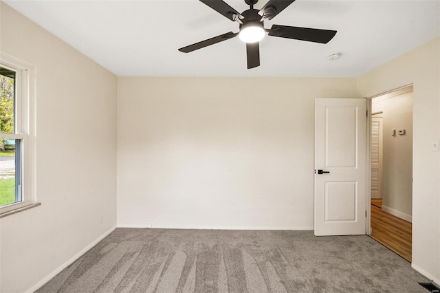 carpeted spare room featuring visible vents, baseboards, and a ceiling fan