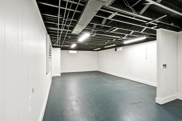 finished below grade area featuring wood walls and stairway