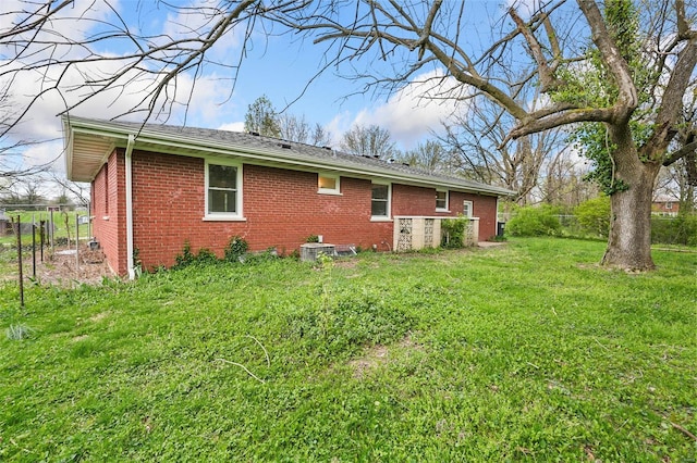 rear view of property with cooling unit, a yard, fence, and brick siding
