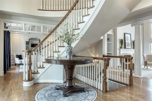 stairs featuring baseboards, a fireplace, wood finished floors, and built in shelves
