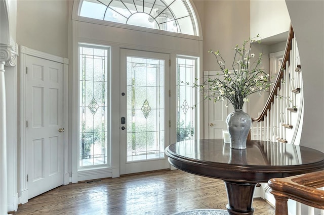 foyer featuring stairs, a towering ceiling, and wood finished floors