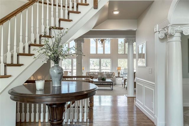interior space with decorative columns, wainscoting, wood finished floors, and a decorative wall