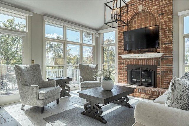 living room with high vaulted ceiling, a brick fireplace, and a chandelier