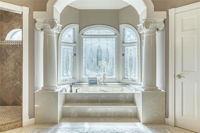interior space with a healthy amount of sunlight, decorative columns, and a garden tub