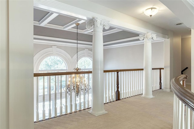 corridor with carpet floors, crown molding, ornate columns, and a notable chandelier