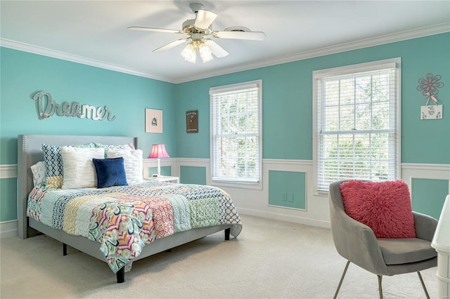 carpeted bedroom with crown molding, a ceiling fan, and wainscoting
