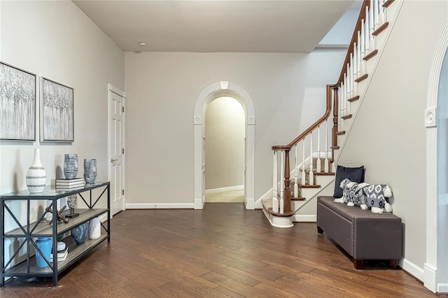 foyer featuring arched walkways, hardwood / wood-style flooring, and stairs
