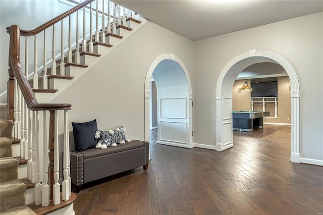 interior space featuring wood-type flooring, arched walkways, baseboards, and stairway