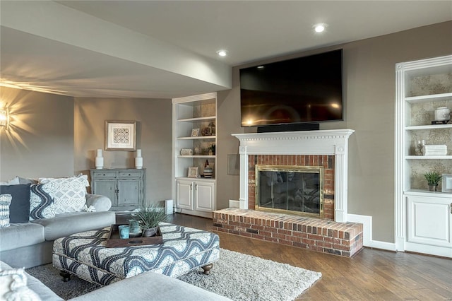 living room with dark wood-type flooring, recessed lighting, a fireplace, and built in shelves