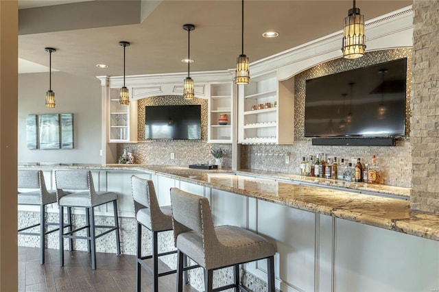 kitchen with decorative backsplash, a breakfast bar area, pendant lighting, light stone countertops, and dark wood finished floors