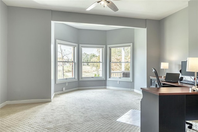 carpeted office space with baseboards, ceiling fan, and a wealth of natural light