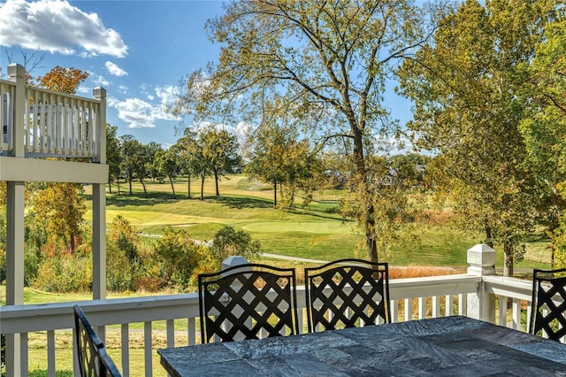 wooden terrace with a yard, view of golf course, and outdoor dining space