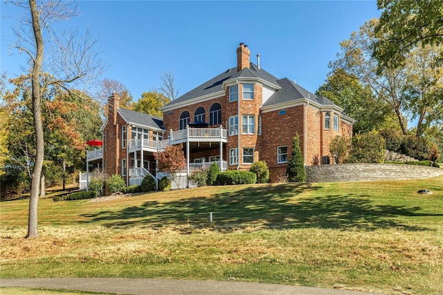 rear view of property with a lawn, a chimney, and brick siding