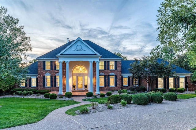 greek revival house with brick siding and a yard