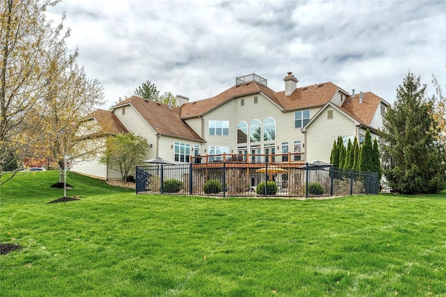 rear view of house with a lawn, fence, and a deck