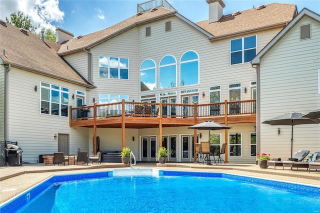back of house featuring a shingled roof, a patio, a chimney, and an outdoor pool