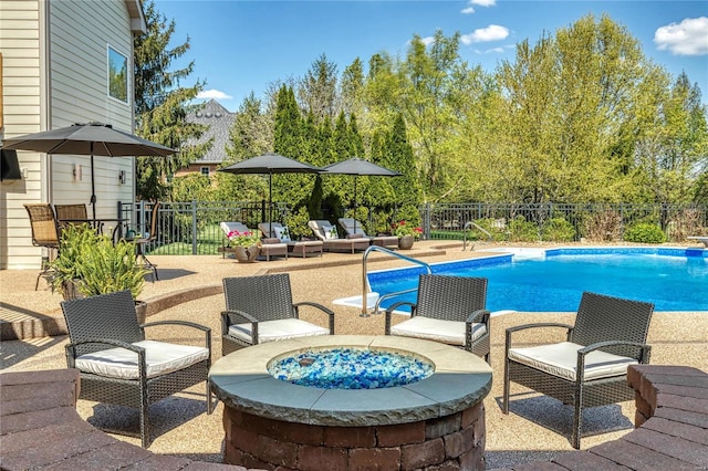 view of swimming pool featuring a fenced in pool, a fenced backyard, a fire pit, and a patio area