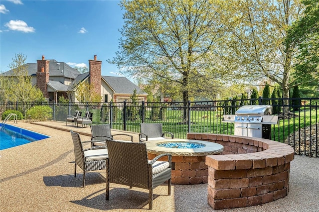 view of patio / terrace with a fenced in pool, a fire pit, fence, and area for grilling