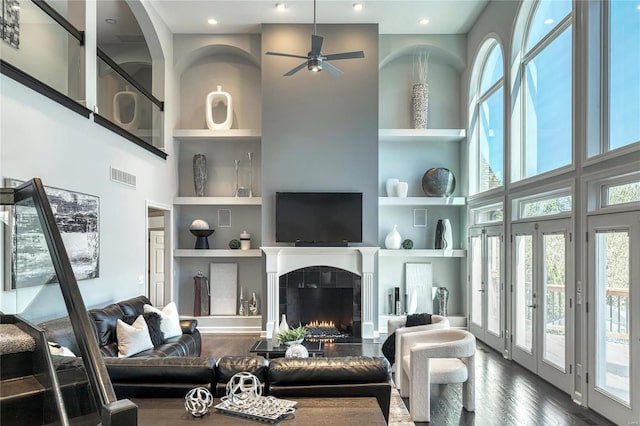 living area with a high ceiling, dark wood finished floors, built in shelves, and visible vents