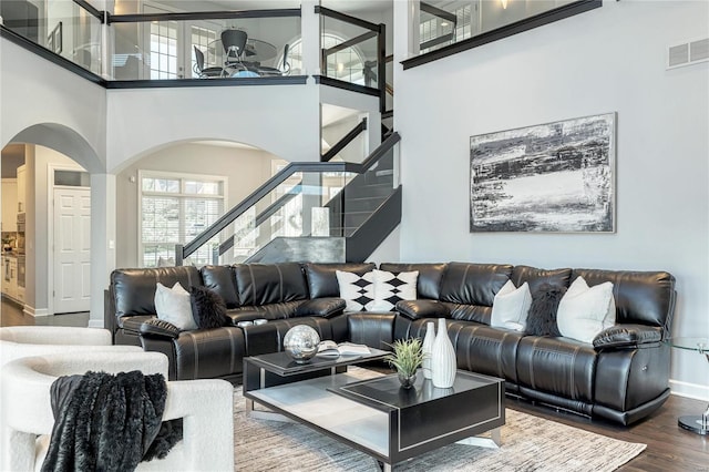 living room featuring stairs, arched walkways, baseboards, and wood finished floors