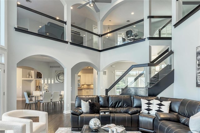 living area featuring ceiling fan, a towering ceiling, wood finished floors, stairway, and a wealth of natural light