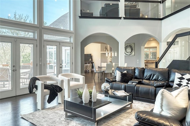 living area featuring french doors, wood finished floors, and a towering ceiling