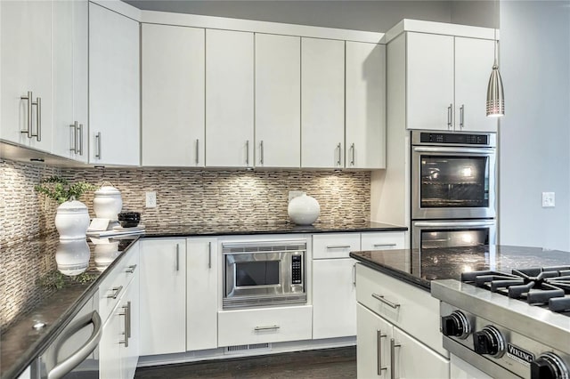 kitchen featuring dark stone counters, white cabinetry, backsplash, and stainless steel appliances