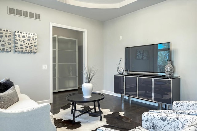 living room featuring visible vents, baseboards, and wood finished floors