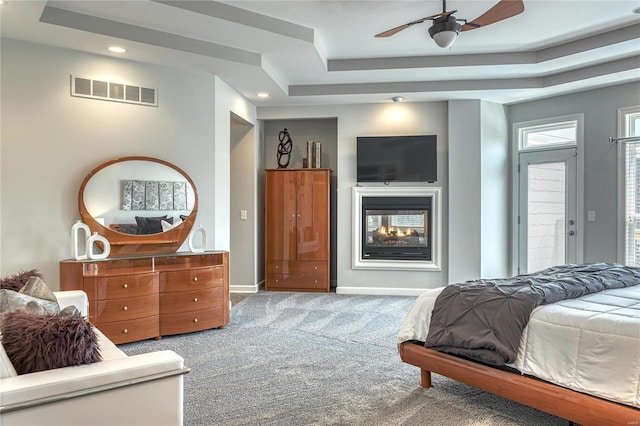 carpeted bedroom with visible vents, baseboards, recessed lighting, a tray ceiling, and a multi sided fireplace