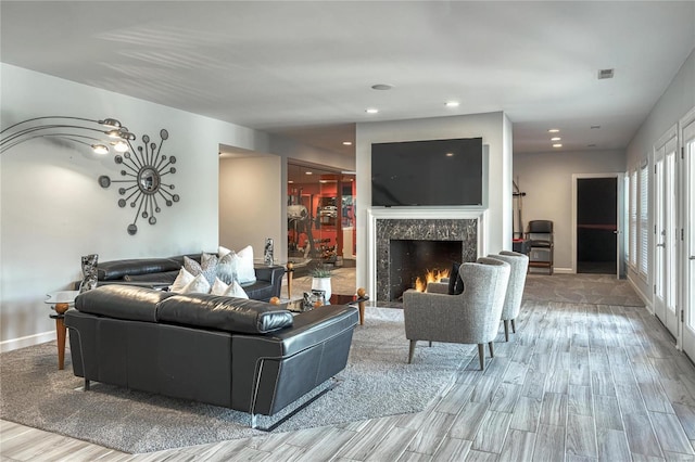 living room featuring recessed lighting, baseboards, wood finished floors, and a fireplace