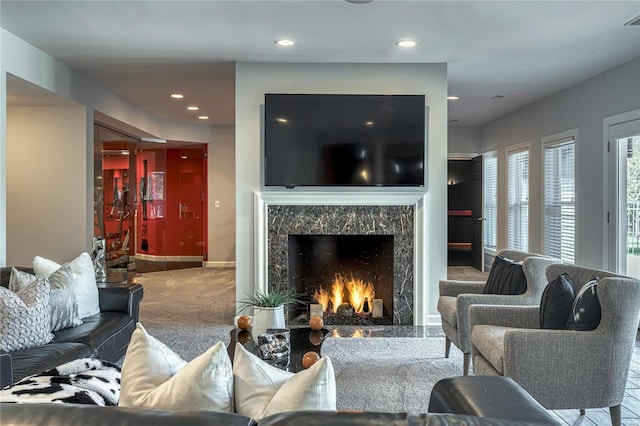 carpeted living room featuring a high end fireplace, baseboards, recessed lighting, and visible vents