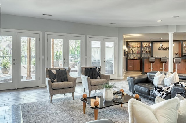 living room with visible vents, bar, french doors, and light wood-type flooring