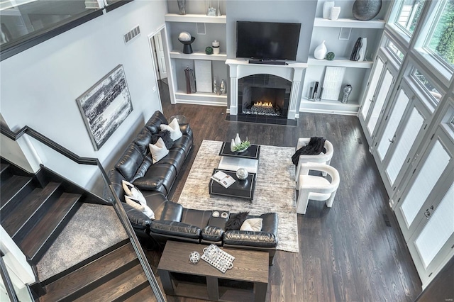 living room with a tiled fireplace, stairway, wood finished floors, and visible vents