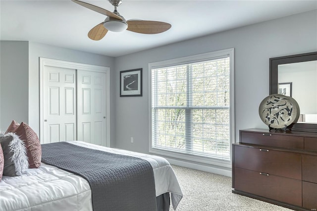 bedroom featuring a closet, multiple windows, a ceiling fan, and light colored carpet