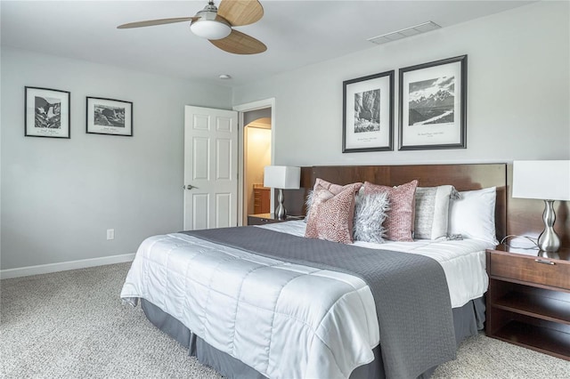 carpeted bedroom featuring arched walkways, baseboards, visible vents, and a ceiling fan