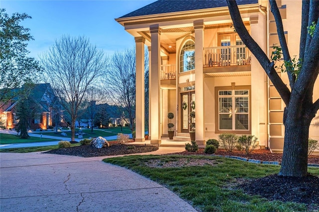 doorway to property featuring roof with shingles, stucco siding, and a balcony