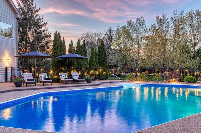 pool at dusk with a patio, fence, and a fenced in pool