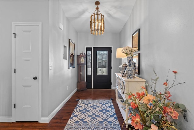 foyer entrance featuring baseboards, wood finished floors, and a notable chandelier