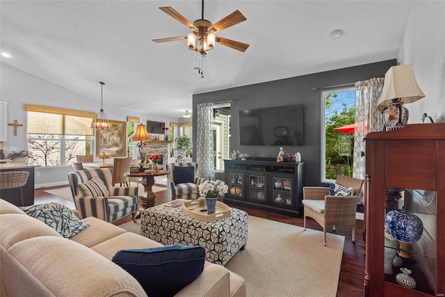 living area with lofted ceiling, wood finished floors, and ceiling fan with notable chandelier