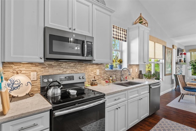 kitchen featuring a sink, stainless steel appliances, dark wood-type flooring, vaulted ceiling, and white cabinets