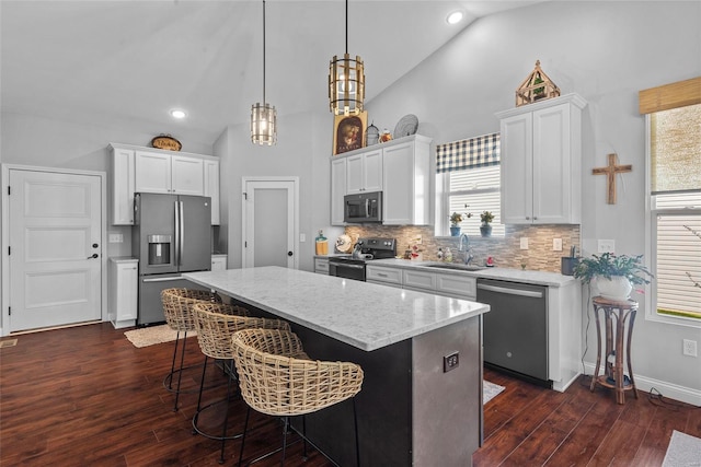 kitchen featuring stainless steel appliances, a kitchen island, white cabinets, and a sink